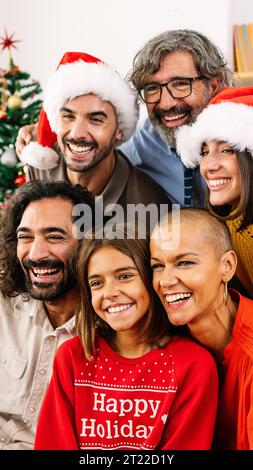 Vertikales Porträt einer glücklichen Familie mit weihnachtsmütze, die gemeinsam weihnachten feiert Stockfoto