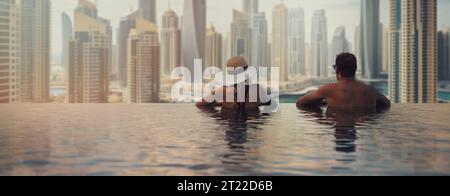 Paare genießen den Panoramablick auf den Jachthafen von Dubai vom Infinity-Pool. Reise in die Vereinigten Arabischen Emirate. Kopierbereich für Banner Stockfoto