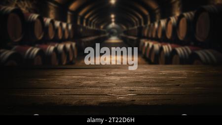 Leere dunkle Holzplatte für Produktpräsentation auf verschwommenem Weingut Weinfässer Keller Hintergrund Stockfoto