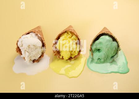 Geschmolzenes Eis in Waffelkegeln auf blassgelbem Hintergrund Stockfoto