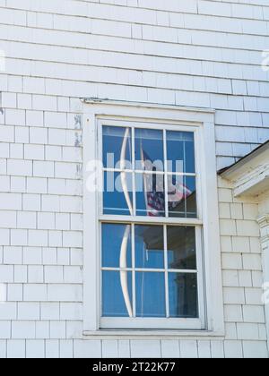 Verzerrte Reflexion der amerikanischen Flagge und des Pols in den Fensterscheiben der Oversand Permit Station am Race Point Beach Stockfoto