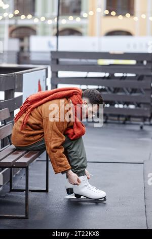 Seitliches Porträt eines Mannes, der im Freien Schlittschuhe auf einer Eislaufbahn auflegt Stockfoto