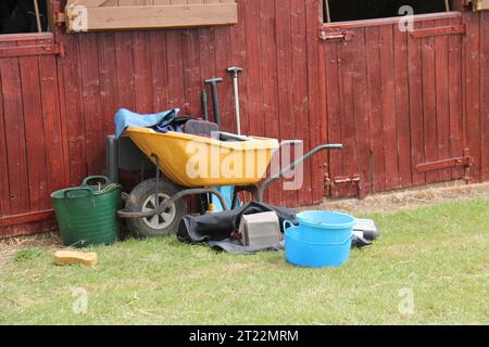 Eine Schubkarre und Werkzeuge für die Pferdepflege in einem Stall. Stockfoto