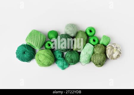 Grüne Strickfäden in verschiedenen Farben auf grauem Hintergrund. Muster der Gewindekugeln. Konzeptnadelarbeit. Flache Lagen Stockfoto
