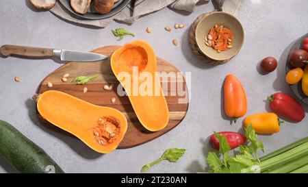 Herbstgemüse auf einer Küchenarbeitsfläche angeordnet, während eine Kürbissuppe zubereitet wird. Stockfoto