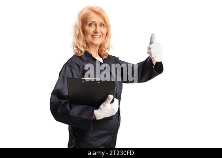 Weibliche Mechanikerin in Uniform, die ein Klemmbrett hält und Daumen isoliert auf weißem Hintergrund nach oben bewegt Stockfoto