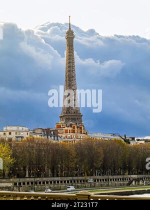 Der ikonische Eiffelturm in Paris, Frankreich, der über die seine im Herbst im goldenen Hell mit dunklen Wolken dahinter gesehen wird Stockfoto