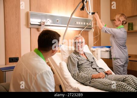 Patient im Schlafanzug kommuniziert mit dem behandelnden Arzt in der Krankenhausstation Stockfoto