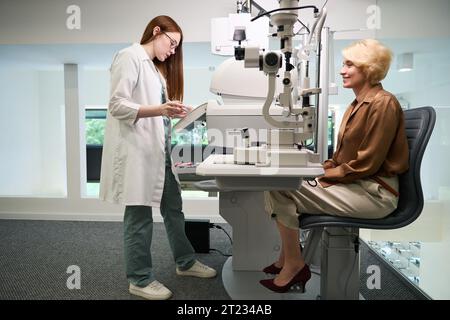 Der rothaarige Arzt berät eine Dame mittleren Alters in einem Diagnosezentrum Stockfoto