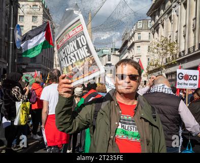 London, Großbritannien. 14. Oktober 2023: Ein Mitglied der Socialist Workers Party hält eine Kopie der Zeitung Socialist Worker bei einer pro-palästinensischen Demonstration in Cent Stockfoto