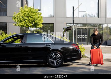 Chauffeur packt einen Koffer in ein Luxusauto Stockfoto