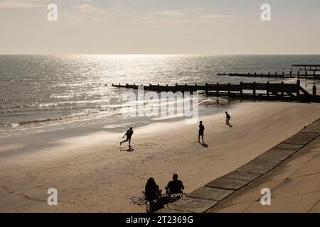 Silhouettenfiguren, die am Strand am Meer Cricket spielen Stockfoto