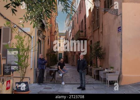 Korsika, Bastia, drei Männer am frühen Morgen warten auf Gäste vor einem Café gegenüber der Zitadelle im Terra Nova Viertel der Stadt. Stockfoto