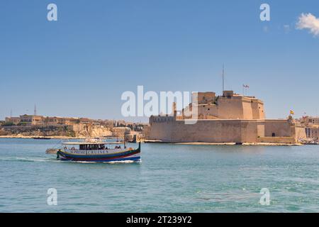 Valletta, Malta - 3. August 2023: Kleines Hafenschiff im Hafen von Valletta. Im Hintergrund befindet sich eine alte Festung. Stockfoto