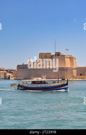 Valletta, Malta - 3. August 2023: Kleines Hafenschiff im Hafen von Valletta. Im Hintergrund befindet sich eine alte Festung. Stockfoto