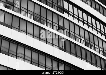 Abstrakter Hintergrund moderner Architektur, weiße Hauswand mit Fenstern in Reihen. Schwarzweißfoto Stockfoto