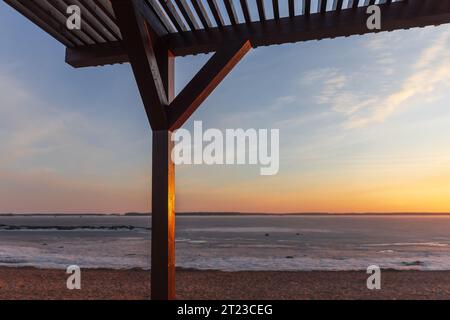 Am Abend ist ein hölzerner Sonnenschirm an der Küste, im Hintergrund liegt die Winterlandschaft des Strandes Stockfoto