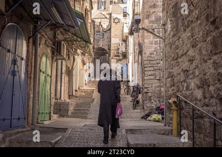Der haredi (ultra-orthodoxe) jüdische Mann läuft die leere Straße in der Altstadt von Jerusalem in Israel hinunter. Stockfoto