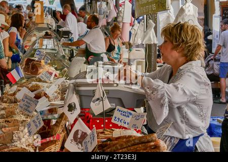 Frau, die auf dem französischen Markt für Würstchen und lokale handgefertigte Waren in Antibes in Südfrankreich arbeitet Stockfoto