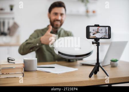 Mann, der den Staubsauger auspackt, während er Videos auf dem Handy aufnimmt Stockfoto