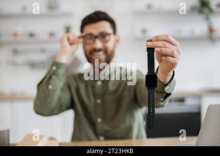 Ein lächelnder Bärenblogger zeigt eine neu gekaufte Smart Watch Stockfoto