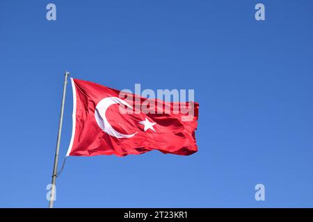 Die türkische Flagge oder die türkische Flagge auf dem blauen Himmel schwenken. Stockfoto
