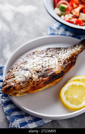 Gebratener dorado-Fisch mit Zitronenscheiben auf weißer Platte. Nahaufnahme Stockfoto