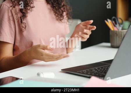 Konzentrieren Sie sich auf die Hände eines cleveren Schülers der Sekundarschule, der etwas vor dem Laptop-Bildschirm erklärt, während Sie im Unterricht Fragen stellen oder beantworten Stockfoto