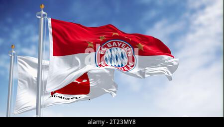 München, DE, 10. Oktober 2023: Bayern München-Flagge winkt an einem klaren Tag mit Bundesliga-Flagge. Professioneller deutscher Fußballverein. Illustratives Editorial 3d Stockfoto