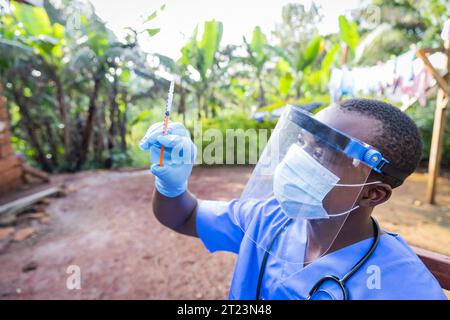Afrikanischer junger Arzt mit Spritze zur Impfvorbereitung. Stockfoto