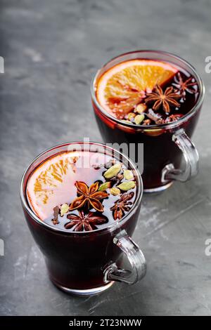 Tassen Glühwein mit Orangenscheibe, Anis, Nelke und Kardamon auf grauem Hintergrund. Kopierbereich Stockfoto