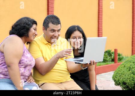 Dunkelhäutige Latino-Papa und -Töchter nutzen ihr Notebook zusammen und verbringen Zeit mit Spielen, Hausaufgaben, Lernen und Videos Stockfoto