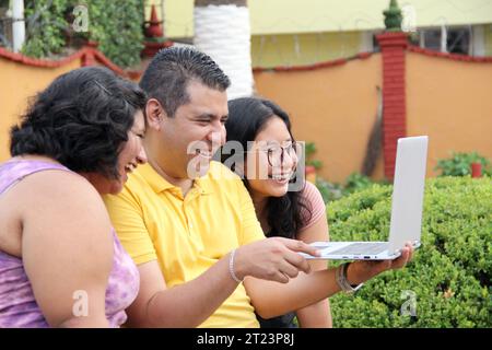 Dunkelhäutige Latino-Papa und -Töchter nutzen ihr Notebook zusammen und verbringen Zeit mit Spielen, Hausaufgaben, Lernen und Videos Stockfoto