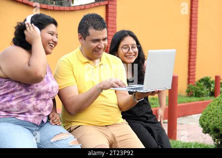 Dunkelhäutige Latino-Papa und -Töchter nutzen ihr Notebook zusammen und verbringen Zeit mit Spielen, Hausaufgaben, Lernen und Videos Stockfoto