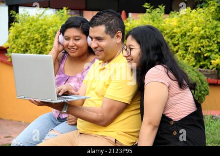 Dunkelhäutige Latino-Papa und -Töchter nutzen ihr Notebook zusammen und verbringen Zeit mit Spielen, Hausaufgaben, Lernen und Videos Stockfoto