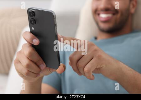 Mann sendet Nachrichten über Smartphone in Innenräumen, selektiver Fokus Stockfoto