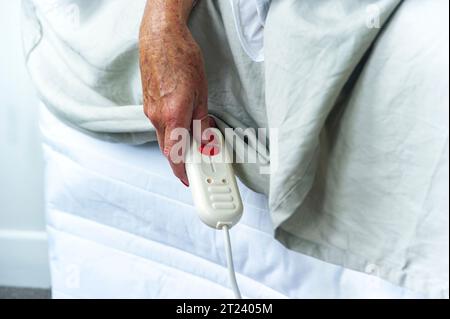 Ältere Frau, die die elektrische Heizdecke ein- oder ausschalten kann Stockfoto