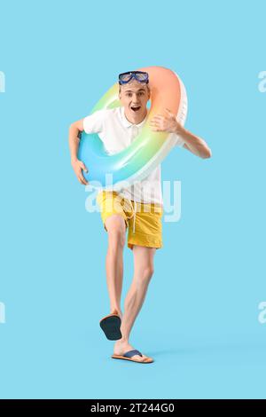 Junger Mann mit Schnorchelmaske und Schwimmring auf blauem Hintergrund Stockfoto