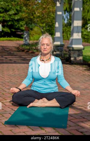 Eine Frau, die Yogalehrerin ist, die Yoga im Freien auf dem Gras macht Stockfoto