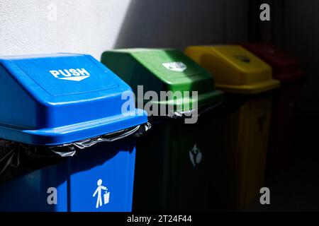 Mehrfarbige Mülltonnen. Papierkorb auf dem Boden und an der weißen Wand. Stockfoto