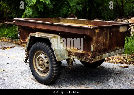 Ein Alter Verlassener Rusty-Traktoranhänger. Traktoranhänger. Ein Alter Trailer Sitzt Auf Der Straße. Stockfoto