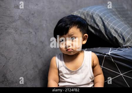 Ein junger asiatischer Junge in seinem Schlafzimmer. Hintergrund für Werbung und Hintergrundbild in der Kinder- und Portraitszene. Tatsächliche Bilder bei Dekorationsideen Stockfoto