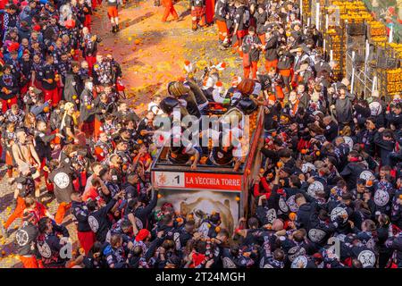 Ivrea, Italien - 19. Februar 2023: Gruppen in traditionellen Dressings und Menschenmenge mit roten Hüten nehmen an der Schlacht der Orangen Teil, Teil des Historors Stockfoto