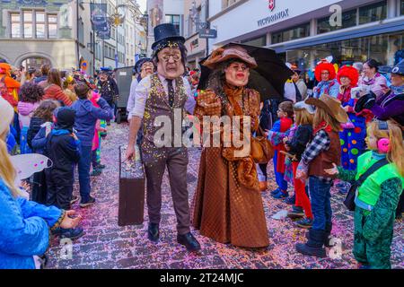 Luzern, Schweiz - 21. Februar 2023: Gruppe von Kostümteilnehmern marschiert auf den Straßen, und Menge, Teil der Kinderparade des Fasnac Stockfoto