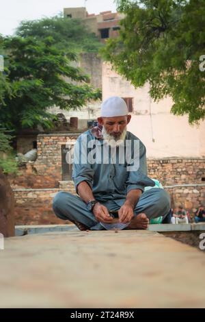 Alte indische Musselin-Anhänger sitzen am Tag an der Wand der Moschee aus einem einzigartigen Winkel Stockfoto
