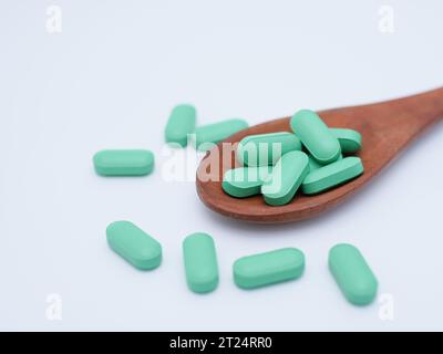 Pillen auf Holzlöffel isoliert auf weißem Hintergrund. Gesundes und medizinisches Konzept Stockfoto