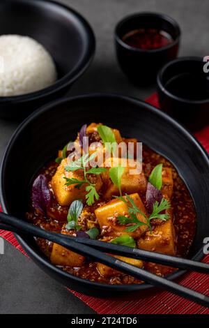 Mapo Tofu Schüssel mit Beilagen auf schwarzem Steintisch Stockfoto