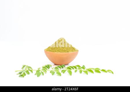 Moringa-Pulver in einer Tonschale mit Blättern auf weißem Hintergrund Stockfoto