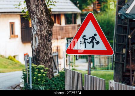 Schulkinder, die das Verkehrszeichen im slowenischen Alpendorf überqueren, selektiver Fokus Stockfoto