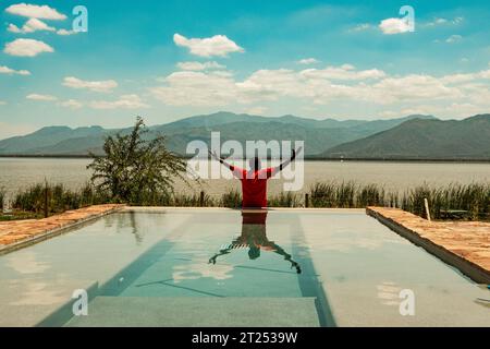 Ein Mann in einem Infinity-Swimmingpool am Lake Jipe im Tsavo West National Park, Kenia Stockfoto